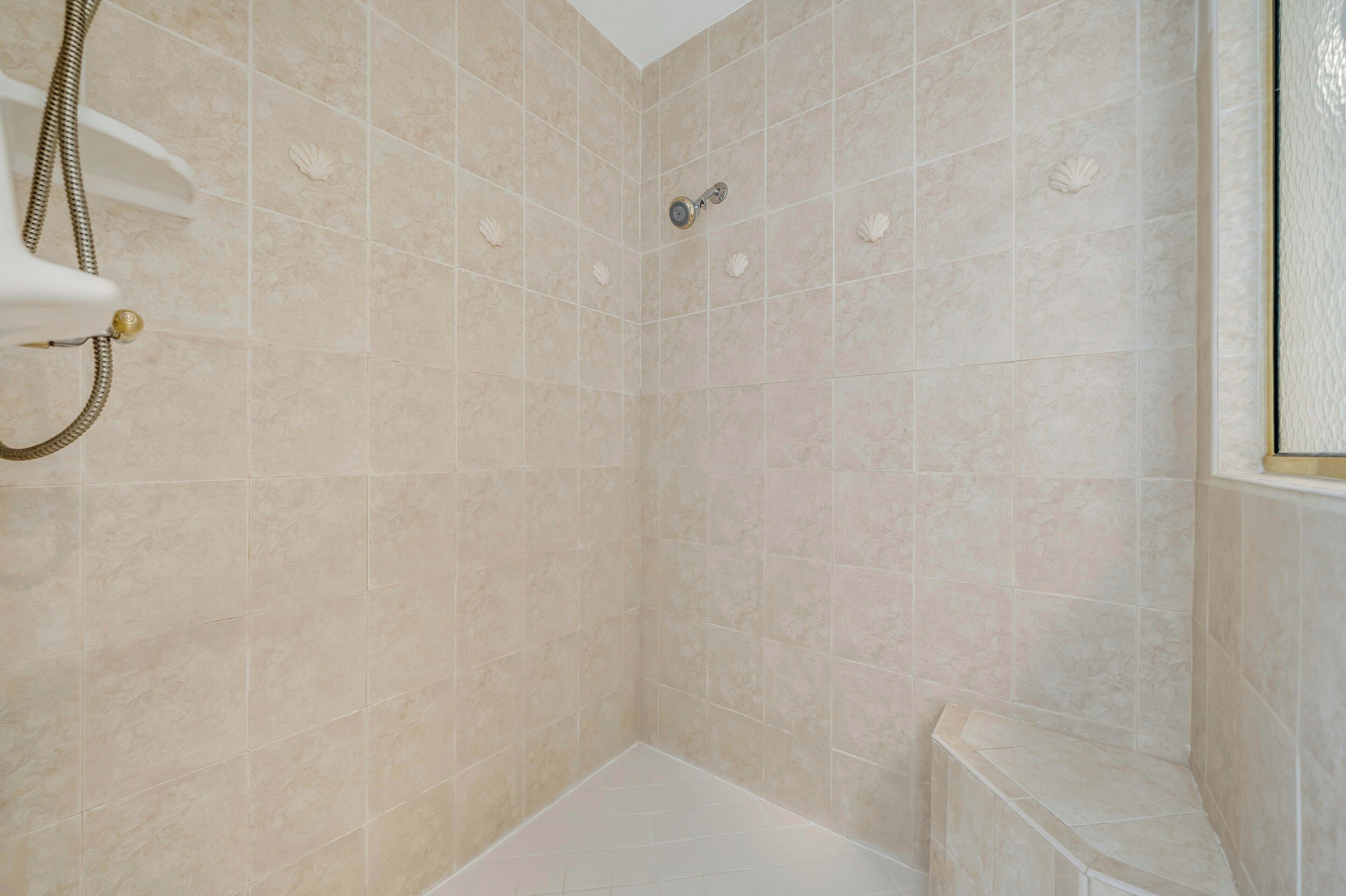 A shower with beige tiles and a handheld showerhead.
