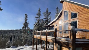 A wooden cabin with a balcony overlooking a snowy forest.