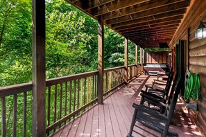 A wooden deck with benches, surrounded by lush greenery.