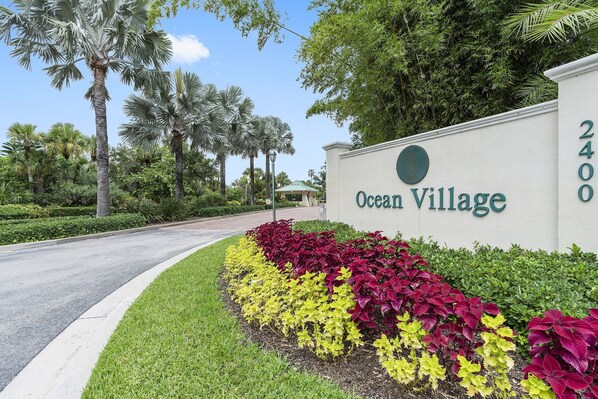 A sign for Ocean Village with a landscaped garden in front.
