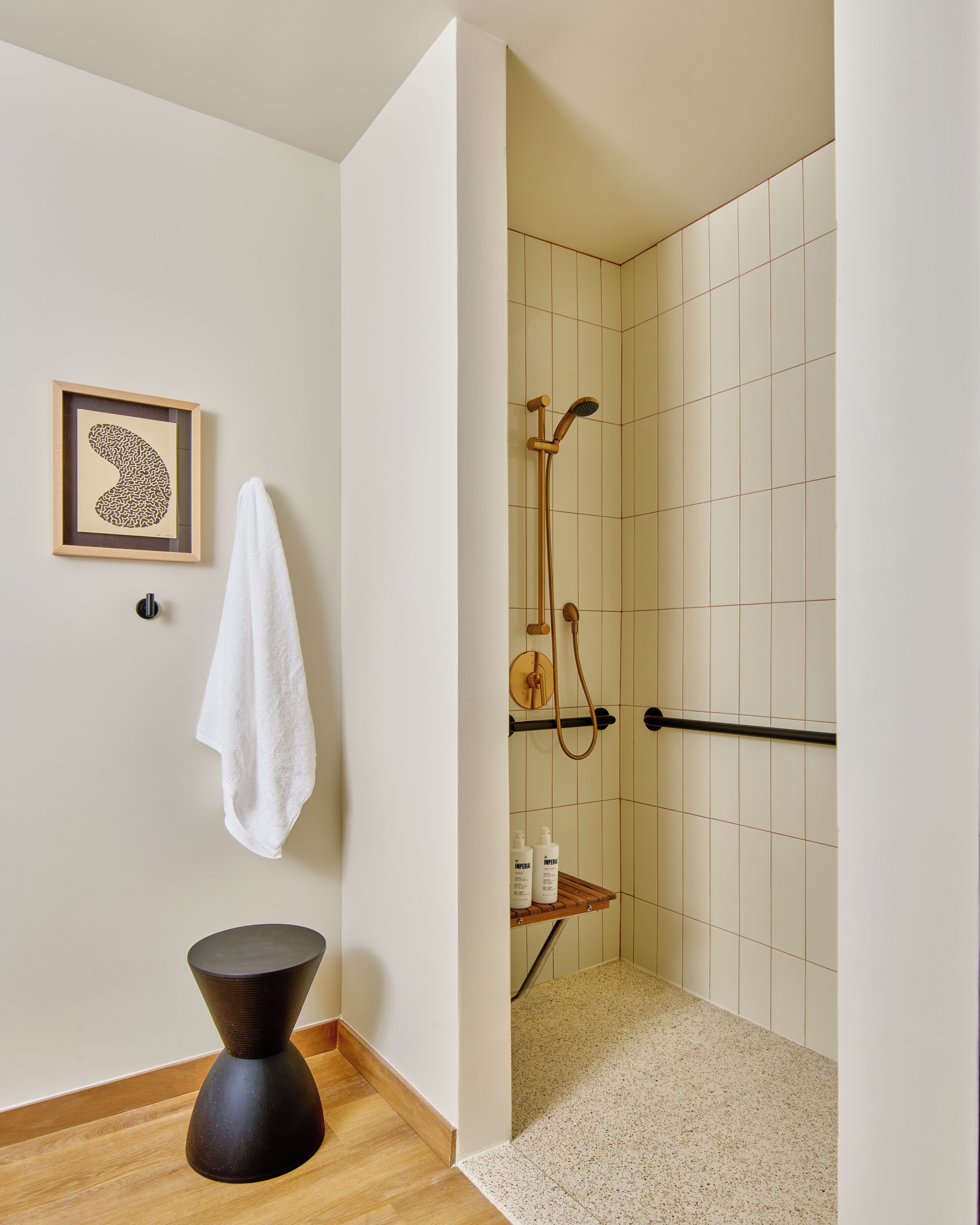 Een badkamer met een douche, toilet, handdoekhouder en een ingelijst foto aan de muur.