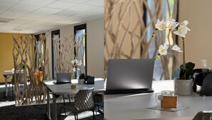 Un espacio de oficina moderno con una computadora portátil sobre un escritorio, una planta en maceta y un vaso de agua.