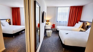 Habitación de hotel con dos camas, un escritorio, una silla y una mesita redonda.