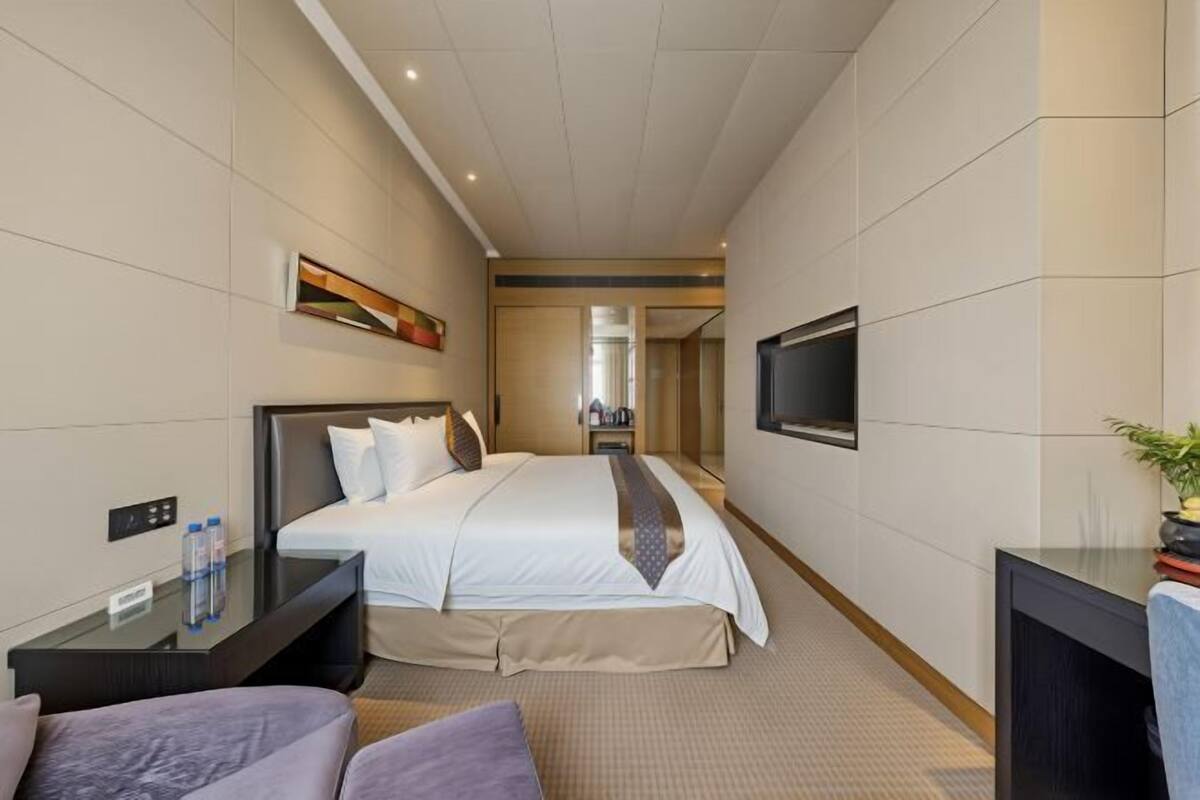 A hotel room with a large bed, a TV, a desk, and a small seating area.
