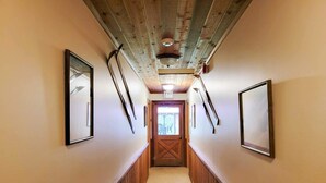 A hallway with wooden paneling, framed pictures on the walls, and a door at the end. - Cedar - pet-friendly room at The Inn At Mazama (Mazama)