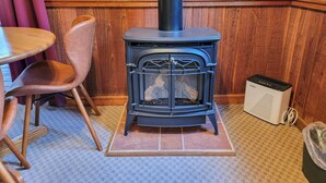 A corner room with a black wood-burning stove, a table with chairs, and a patterned wallpaper. - Cedar Plus - large room at The Inn At Mazama (Mazama)