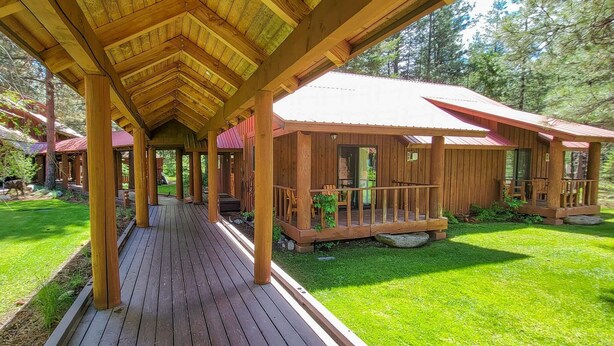 A wooden cabin with a covered deck and a fenced yard. - Cedar Plus - large room at The Inn At Mazama (Mazama)