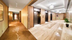 A hotel lobby with a marble floor, wooden walls, and a potted plant. - Jinjiang Metropolo Hotel (Shanghai Jing'an Pengpu Xincun Subway Station) (Shanghai)