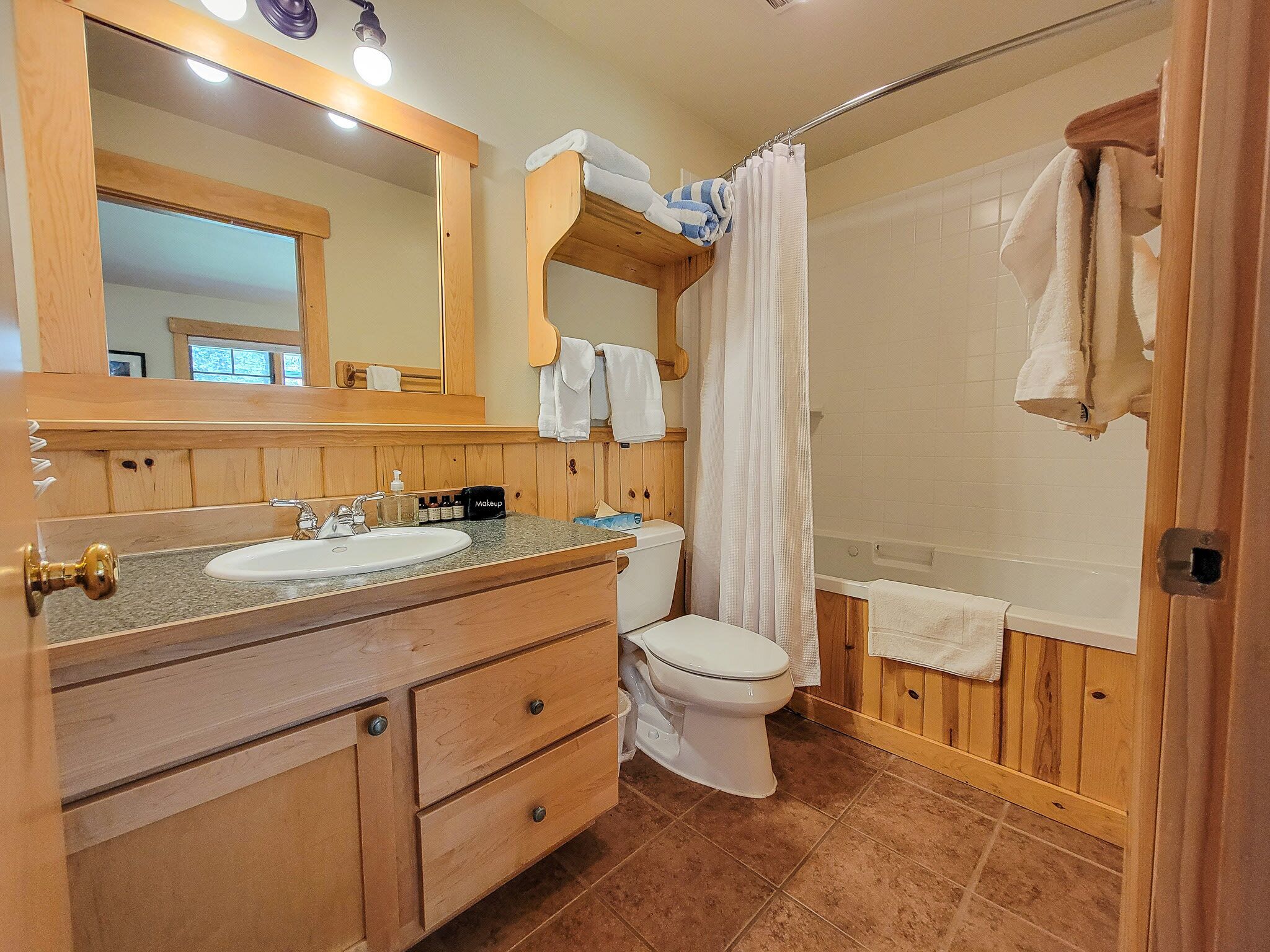 Une salle de bain avec un meuble-lavabo en bois, un évier, des toilettes et un espace douche.