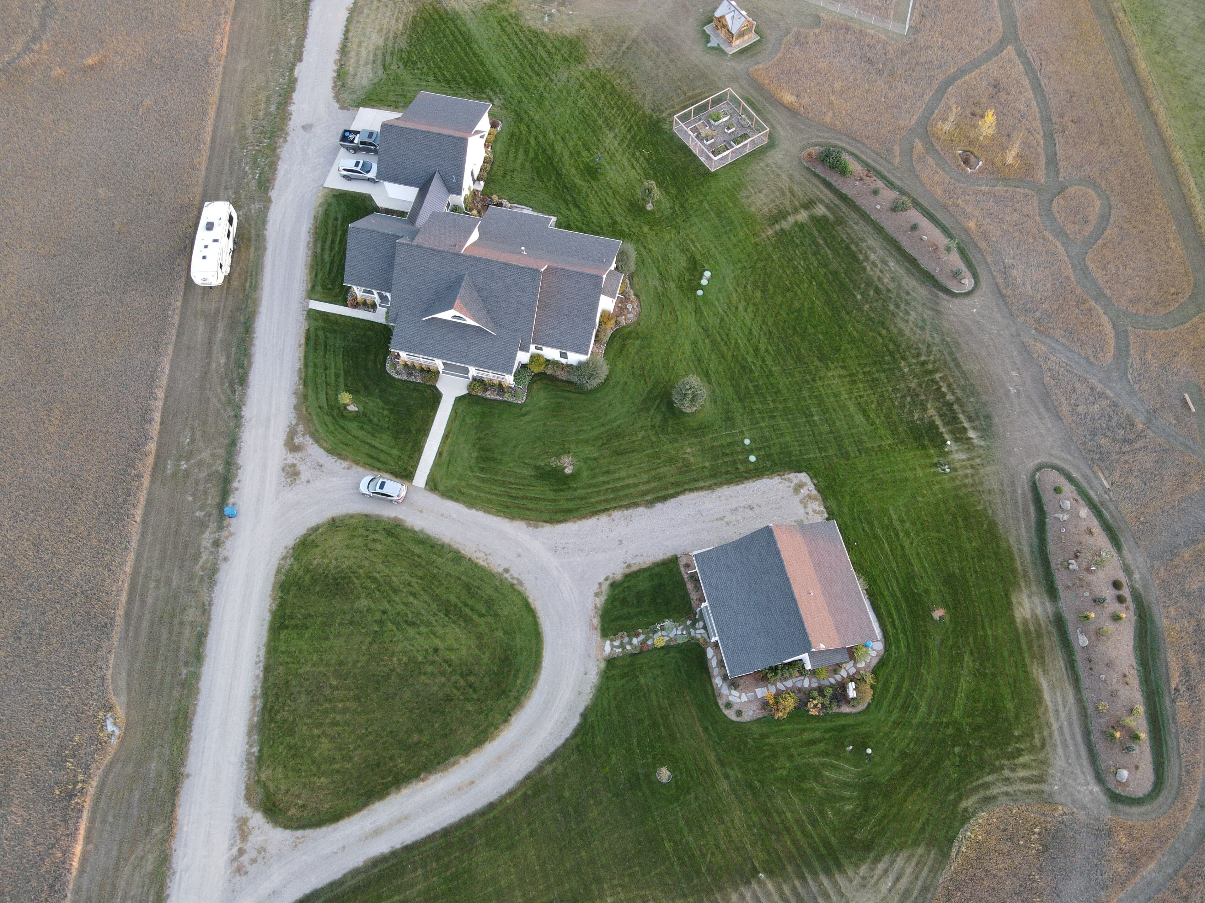 An aerial view of a residential area with multiple houses, roads, and a small parking area.