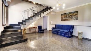 Un interior moderno con una escalera, un sofá azul y un cuadro en la pared.
