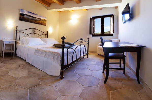 A bedroom with a bed, bedside table, chair, and a desk with a chair. - Arucimeli Country House (Giarratana)