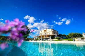 A large, two-story building with a pool in the foreground. - Arucimeli Country House (Giarratana)