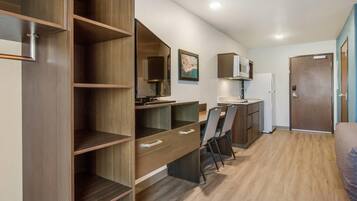 Una kitchenette compacta con microondas, refrigerador y un pequeño comedor con sillas.