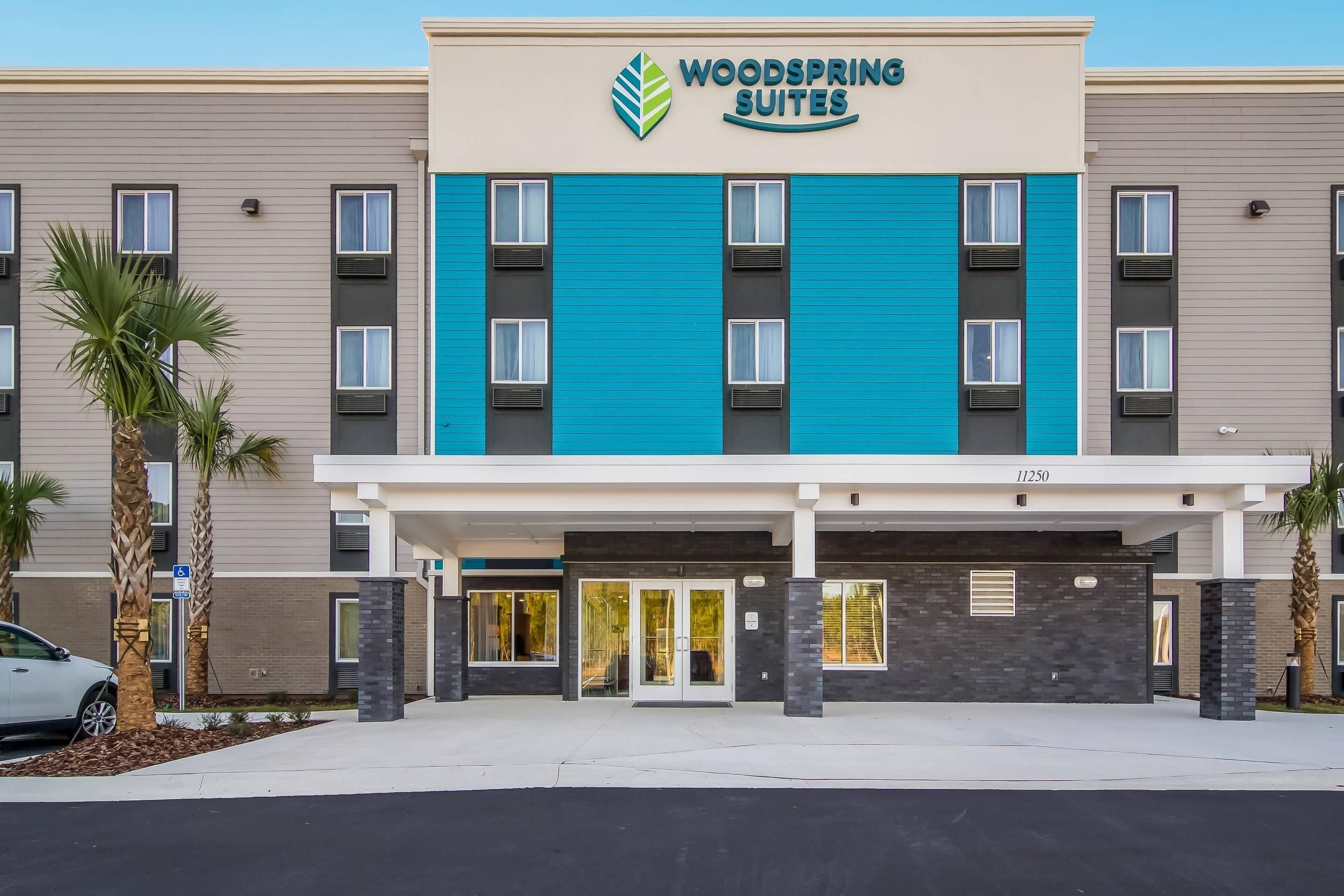 Un hotel con fachada moderna, un logotipo destacado y una entrada visible.