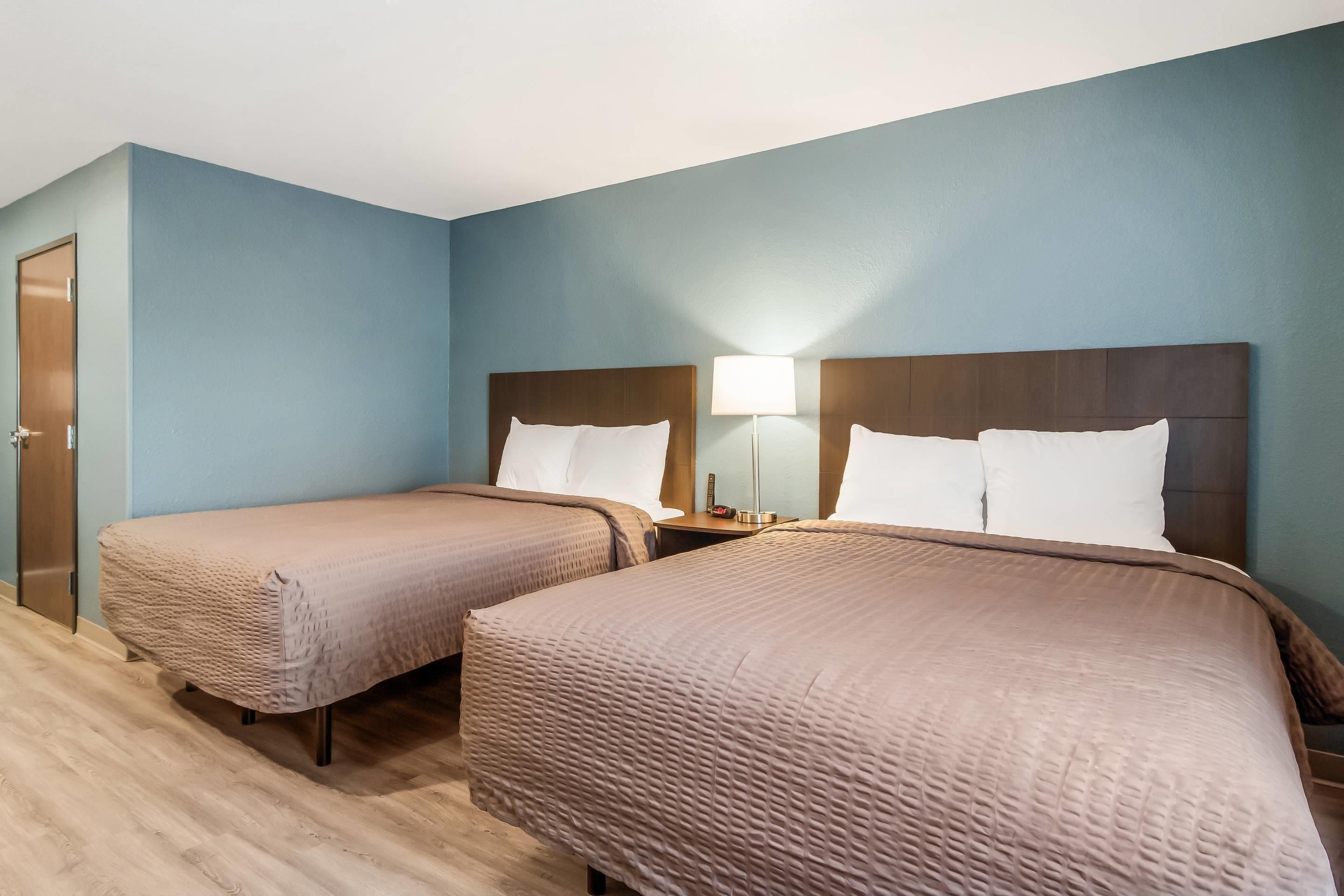 Habitación de hotel con dos camas, piso de madera y pared azul.