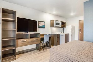 A compact hotel room with a bed, a desk, a television, a microwave, and a refrigerator. - WoodSpring Suites Jacksonville Baymeadows (Jacksonville)