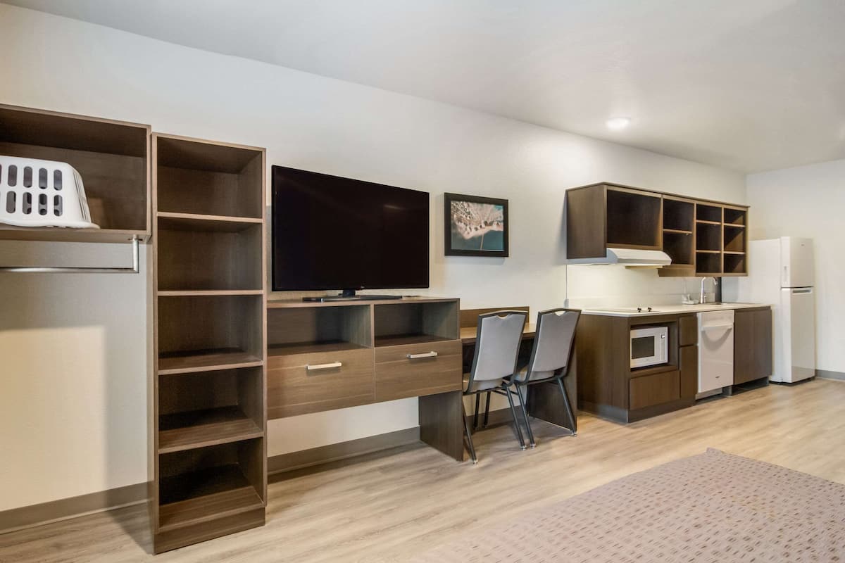 A modern kitchen with built-in appliances, a dining area with chairs, and a TV.