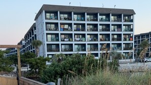 A multi-story building with balconies, a wooden boardwalk, and surrounding vegetation. - OCEANFRONT 1st floor unit! 150 steps away from the sand AND multiple pools!! (Myrtle Beach)