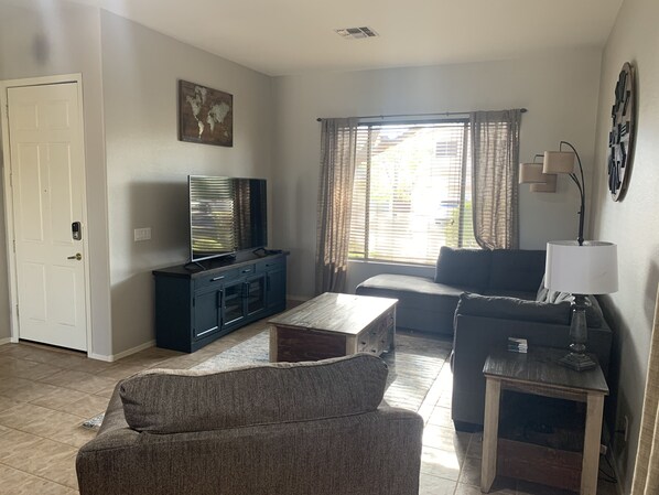 A living room with a TV, sofa, and coffee table. - Four bedroom home on golf course. (Mesa)