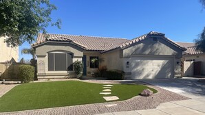 A residential house with a tiled roof, a garage, and a well-maintained lawn with stepping stones. - Four bedroom home on golf course. (Mesa)