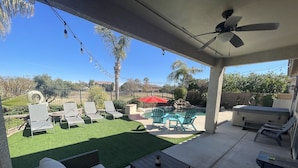 A covered patio with artificial grass, outdoor furniture, a pool, and a hot tub. - Four bedroom home on golf course. (Mesa)
