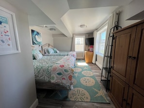 Una camera da letto con due letti, un armadio in legno, una televisione e un quadro appeso al muro.