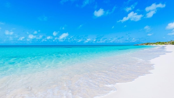 Ein Strand mit klarem türkisblauem Wasser und weißem Sand.