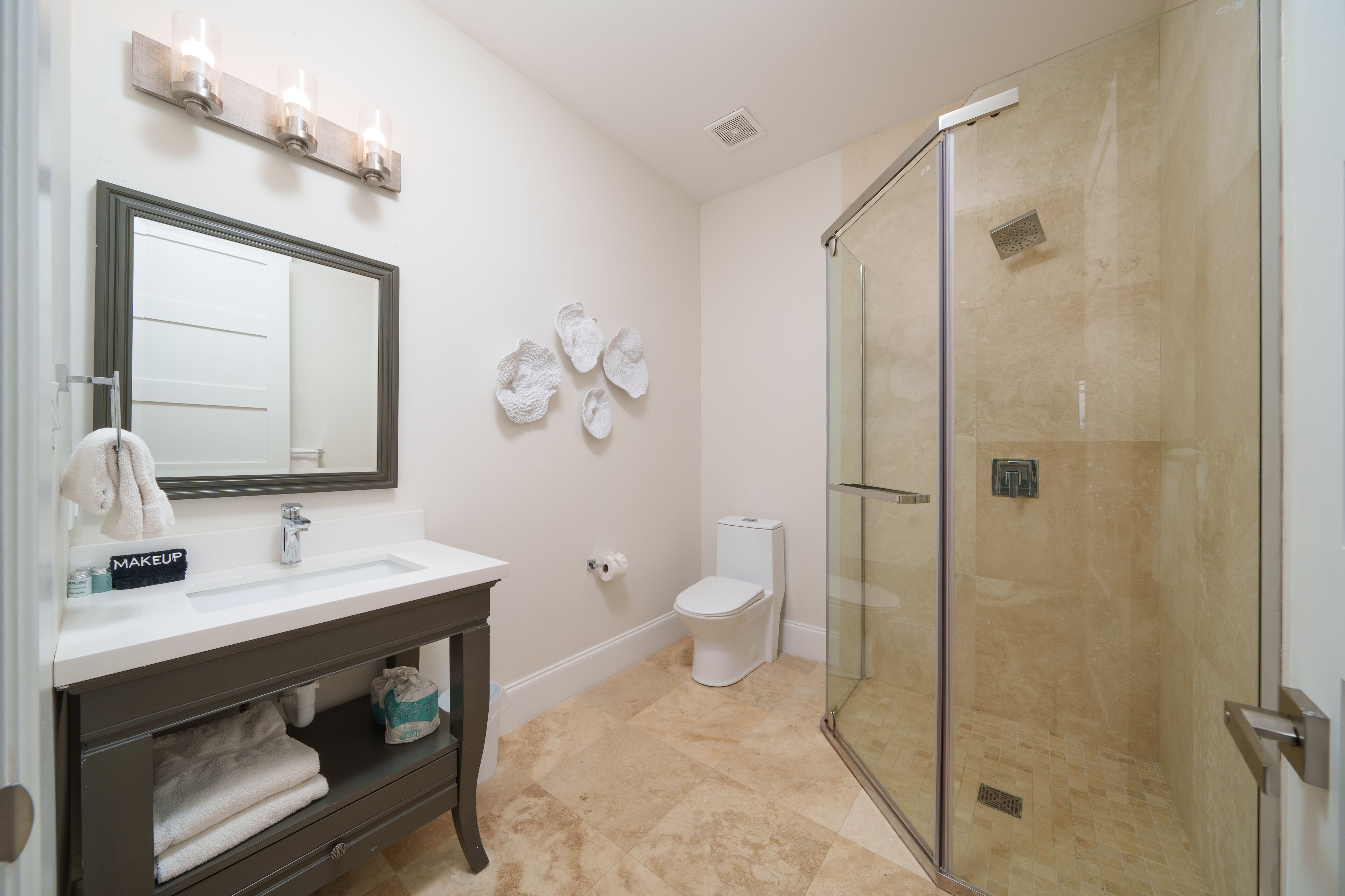Un baño con ducha de vidrio, un lavabo blanco y un espejo grande.