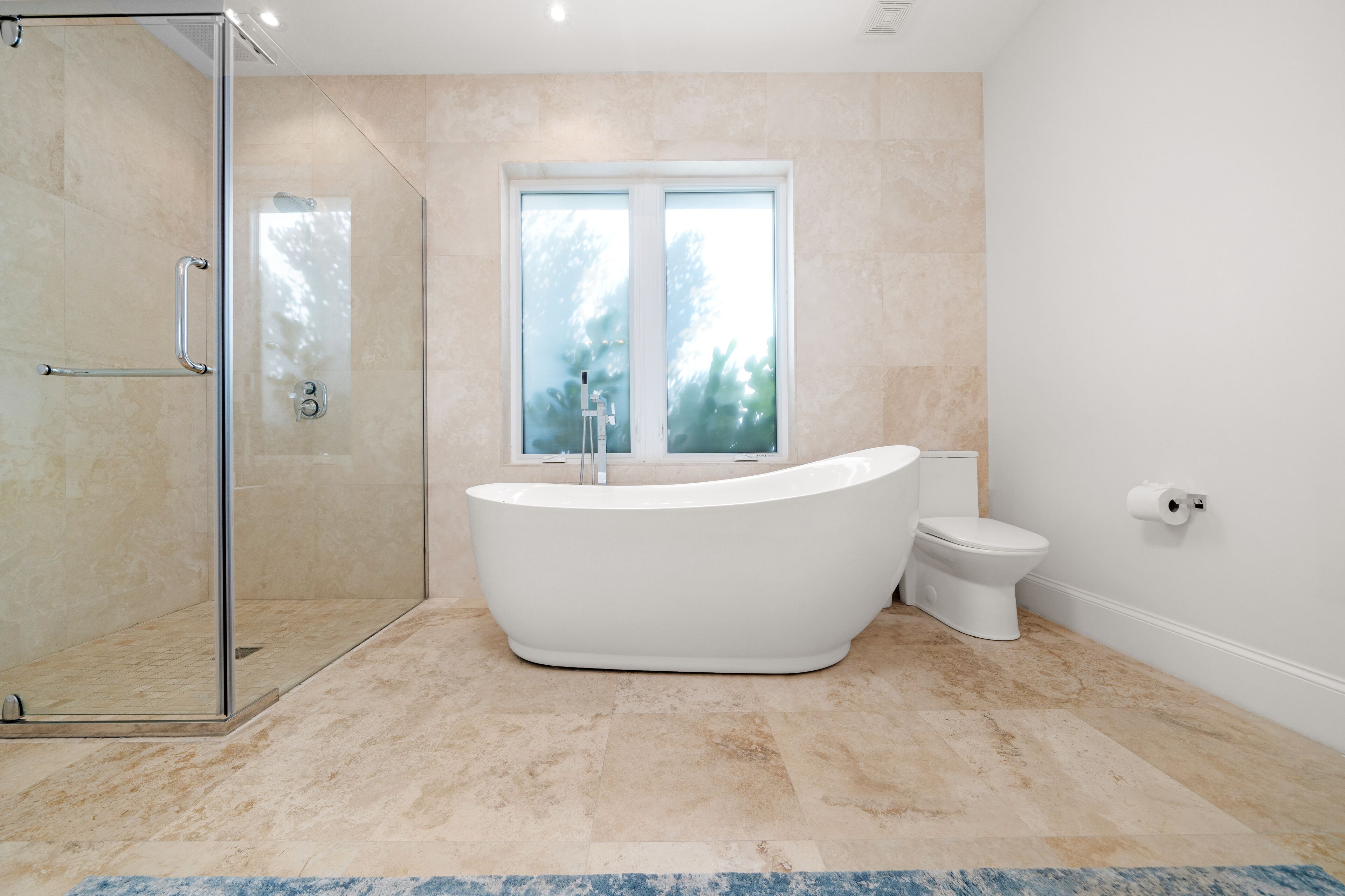 A modern bathroom with a freestanding bathtub, a glass-enclosed shower, and a toilet.