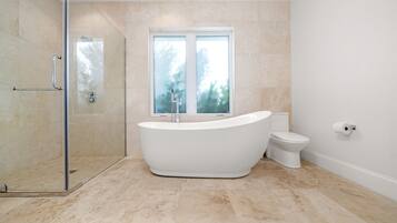 A modern bathroom with a freestanding bathtub, a glass-enclosed shower, and a toilet.