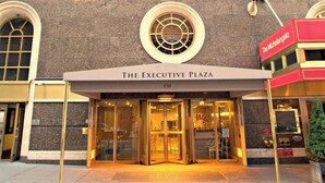 The entrance to The Executive Plaza, featuring a glass door entrance, a prominent circular window above the entrance, and a red awning with the name 'The Michelangelo' to the right.