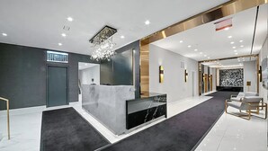 A modern reception area with a marble reception desk, a chandelier, and a carpeted floor.