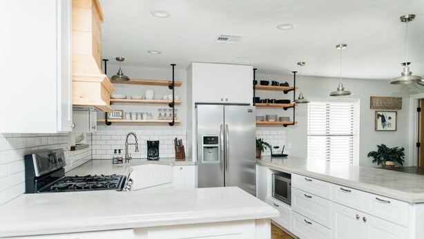 Una cocina moderna con armarios blancos, un refrigerador de acero inoxidable y repisas de madera.