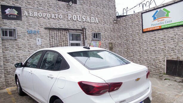 A white Chevrolet Cruze parked in front of a building with a sign reading "AEROPORTO POUSADA". - Casa Aeroporto Pousada (Recife)