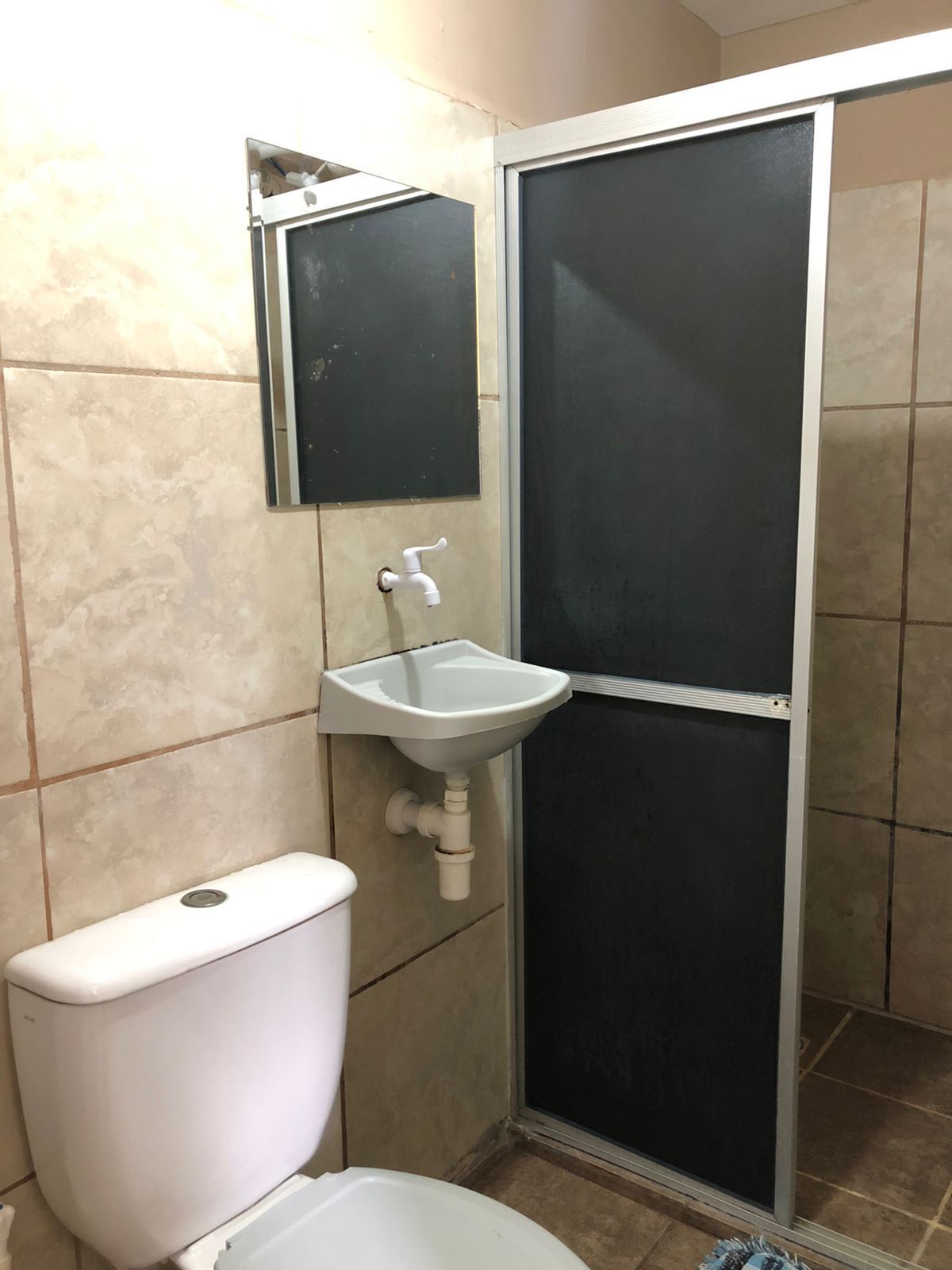 Un baño con inodoro, lavamanos y cabina de ducha.