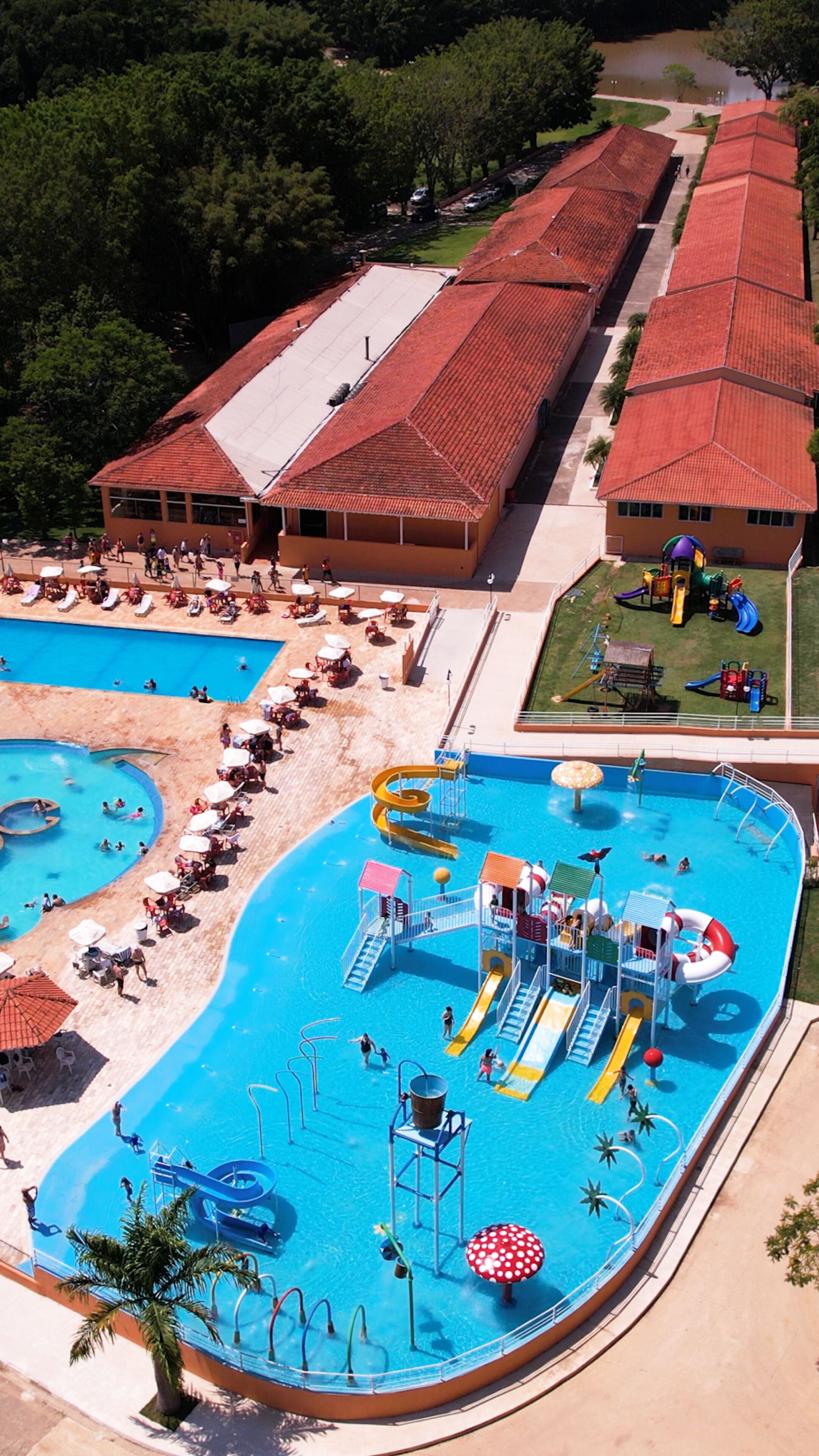 Una grande piscina con scivoli e giochi d'acqua, circondata da zone relax e un edificio coperto.