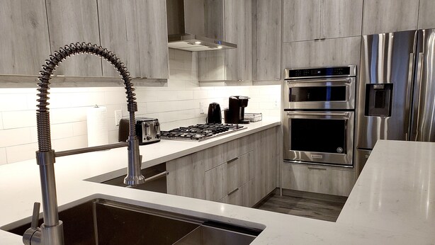 Una cocina moderna con electrodomésticos de acero inoxidable, horno empotrado y pileta de acero inoxidable.