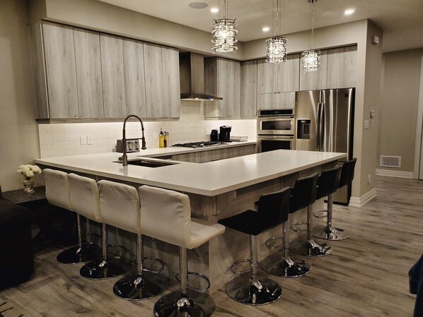 Una cocina moderna con una isla grande, electrodomésticos de acero inoxidable y taburetes de bar.