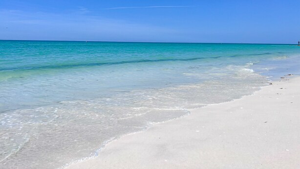 A beach with clear turquoise water and white sand.