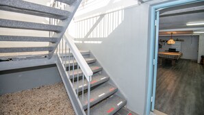 A staircase with metal railings leading to a room with a table and a hanging light fixture.