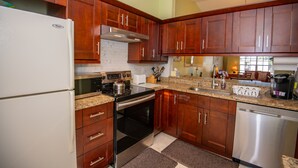 A kitchen with wooden cabinets, a stainless steel refrigerator, a stove, and a dishwasher.