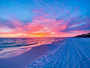 A beach with a clear sky and footprints in the sand.