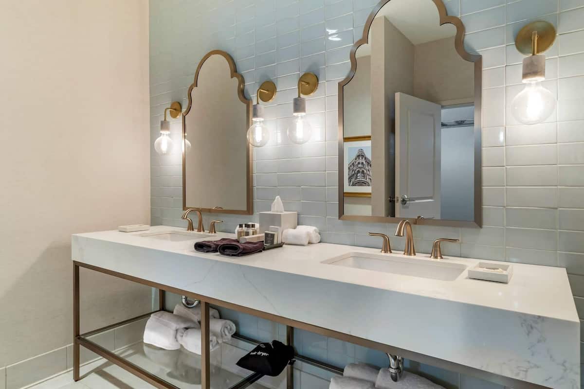 A modern bathroom with a long vanity, two sinks, and a glass-enclosed shower area.