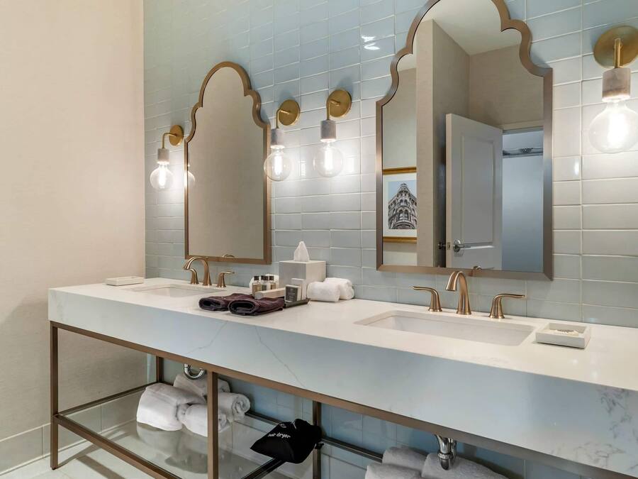 Une salle de bain moderne dotée d’un long meuble-lavabo, de deux vasques et d’une douche à l’italienne.