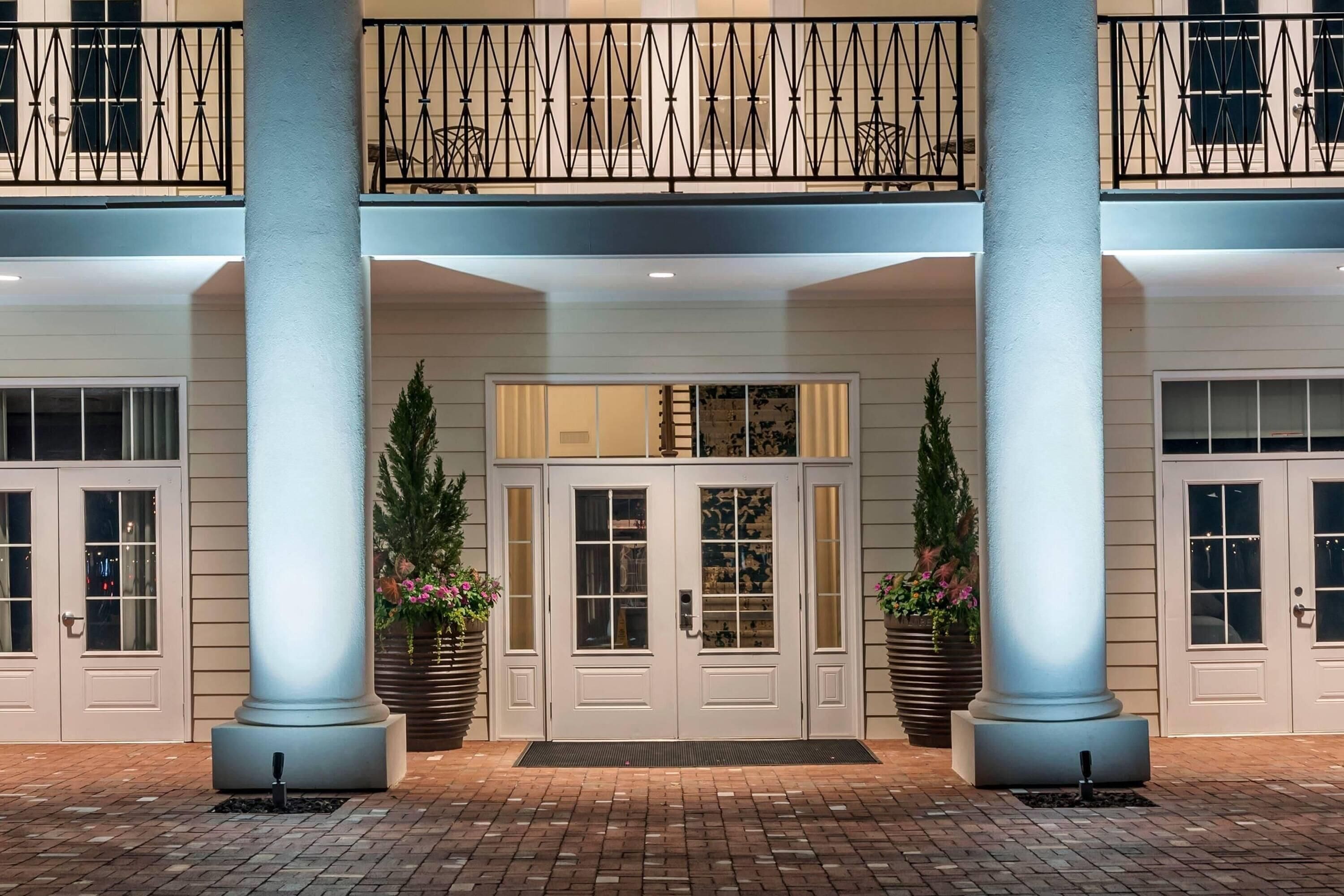 A hotel entrance with a double door, two large columns, and a balcony with a railing.