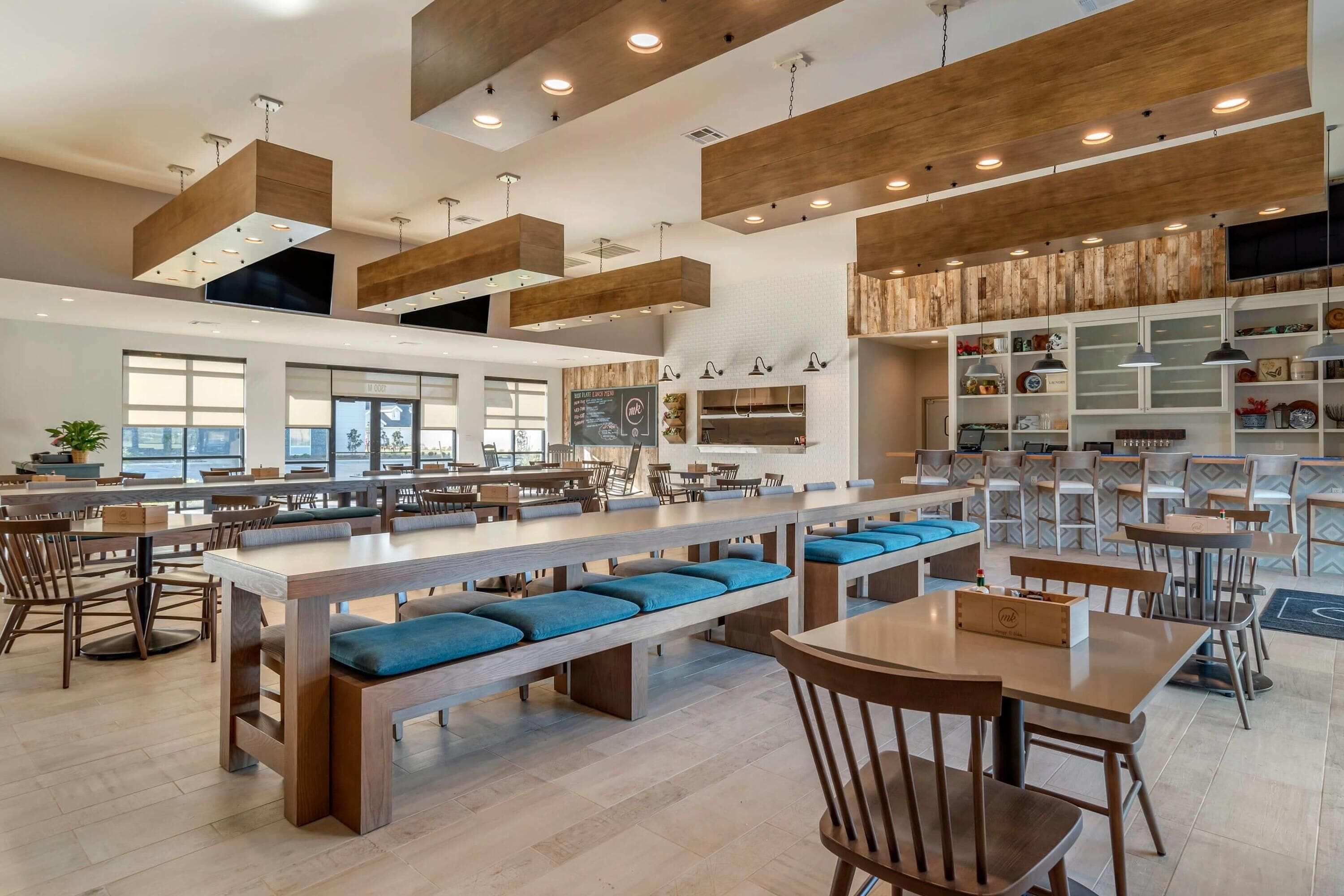 A spacious restaurant with high ceilings, wooden beams, and modern lighting fixtures.