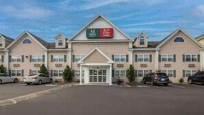 A hotel with a central entrance, multiple windows, and a parking lot with cars. - Econo Lodge Auburn I-95 (Auburn)