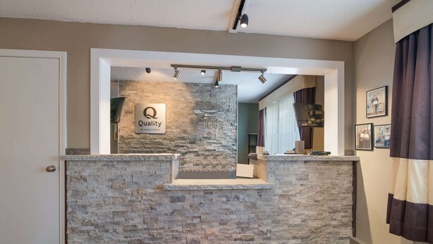 A reception area with a stone wall, a sign reading "Quality by Choice Hotels," and a red carpet with "EconoLodge" text. - Econo Lodge Auburn I-95 (Auburn)