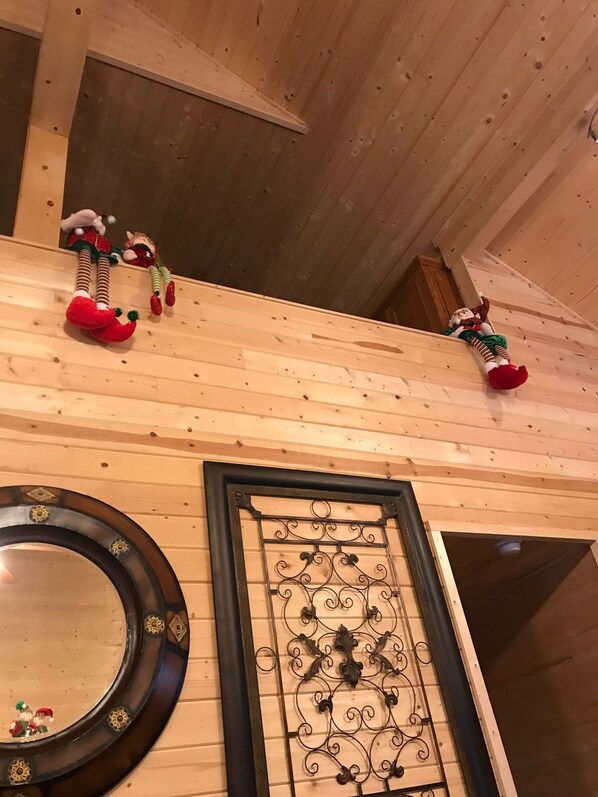 A wooden ceiling with two elf dolls and a decorative mirror.